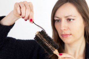 Dark-haired woman being sad, because of having problems with hair loss